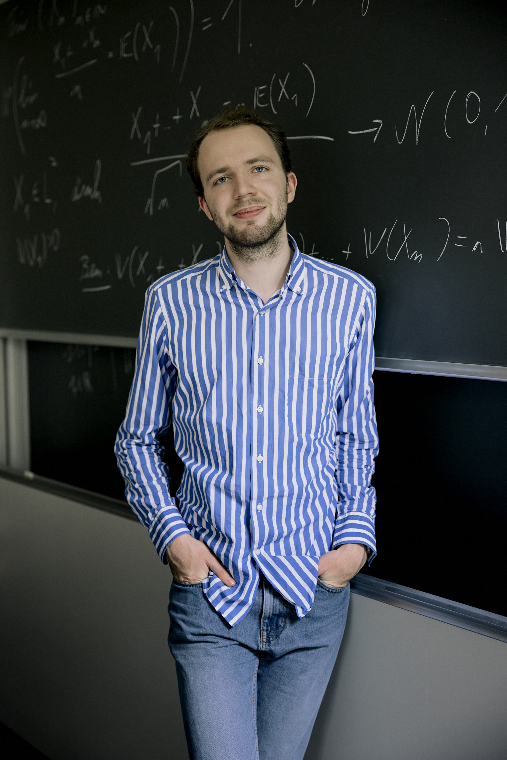 Maximilian Janisch in front of a blackboard with mathematical formulas
